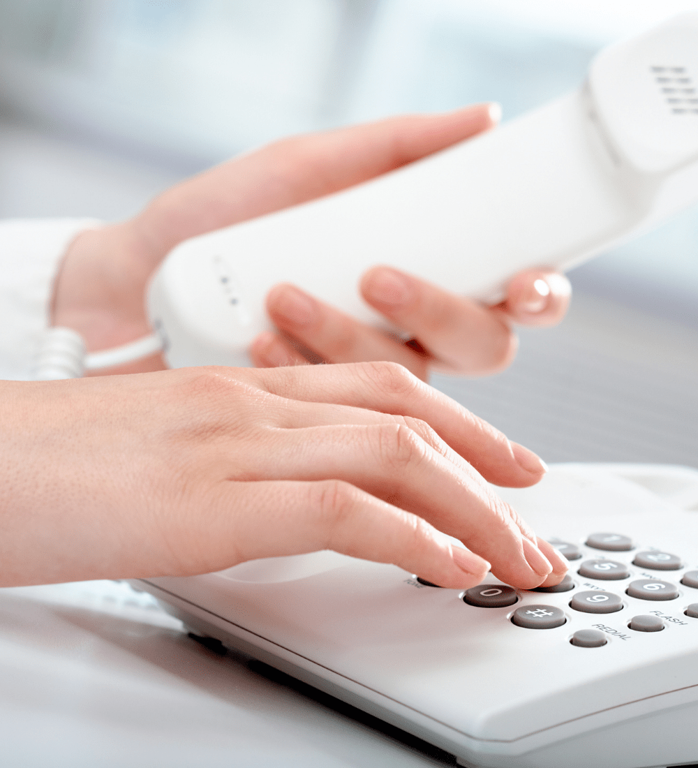 a set of womans hands lifting a white phone and dialing